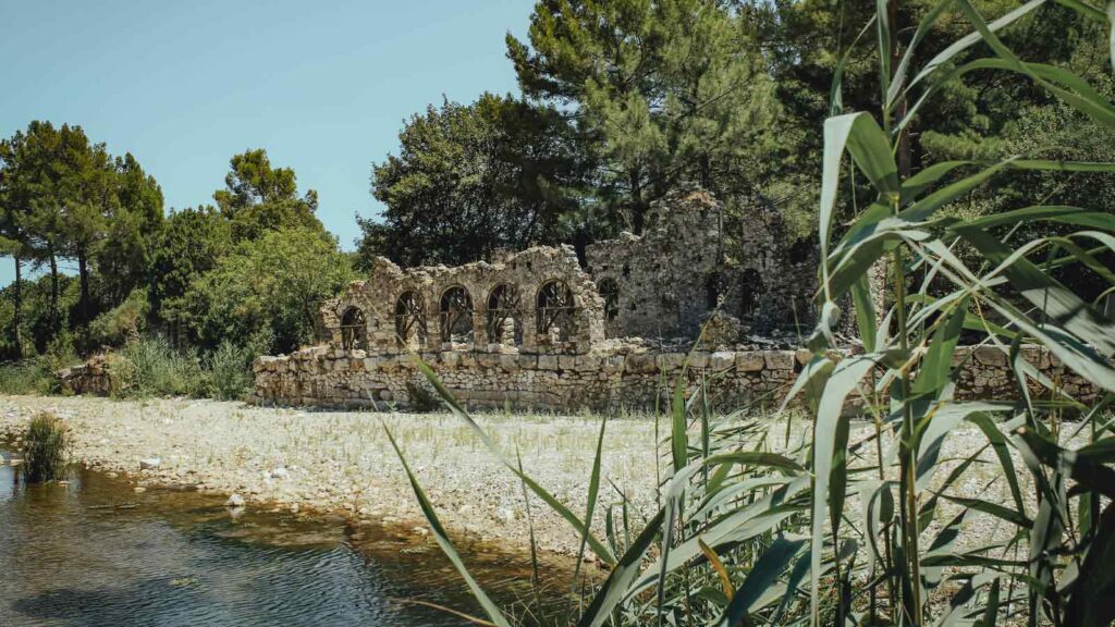 Phaselis ancient Roman harbor ruins with stone columns standing in shallow turquoise water along Mediterranean coastline