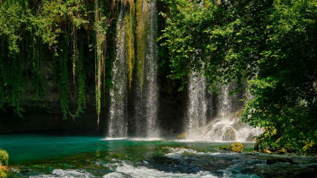 Lower Düden Waterfall cascading dramatically over cliff into turquoise Mediterranean Sea with rainbow mist