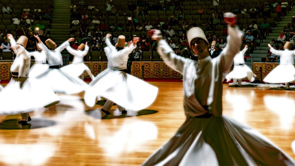 Whirling dervish performer in white robes spinning during traditional Turkish night cultural show with live music