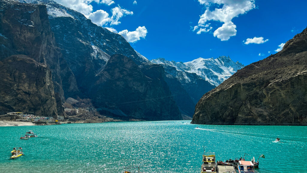 Crystal clear turquoise waters of Attabad Lake with mountain reflections and traditional wooden boats